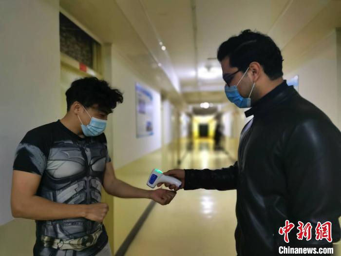 来自阿富汗的太原理工大学汉语国际教育专业学生王伟为同学测量体温。　高雨晴 摄